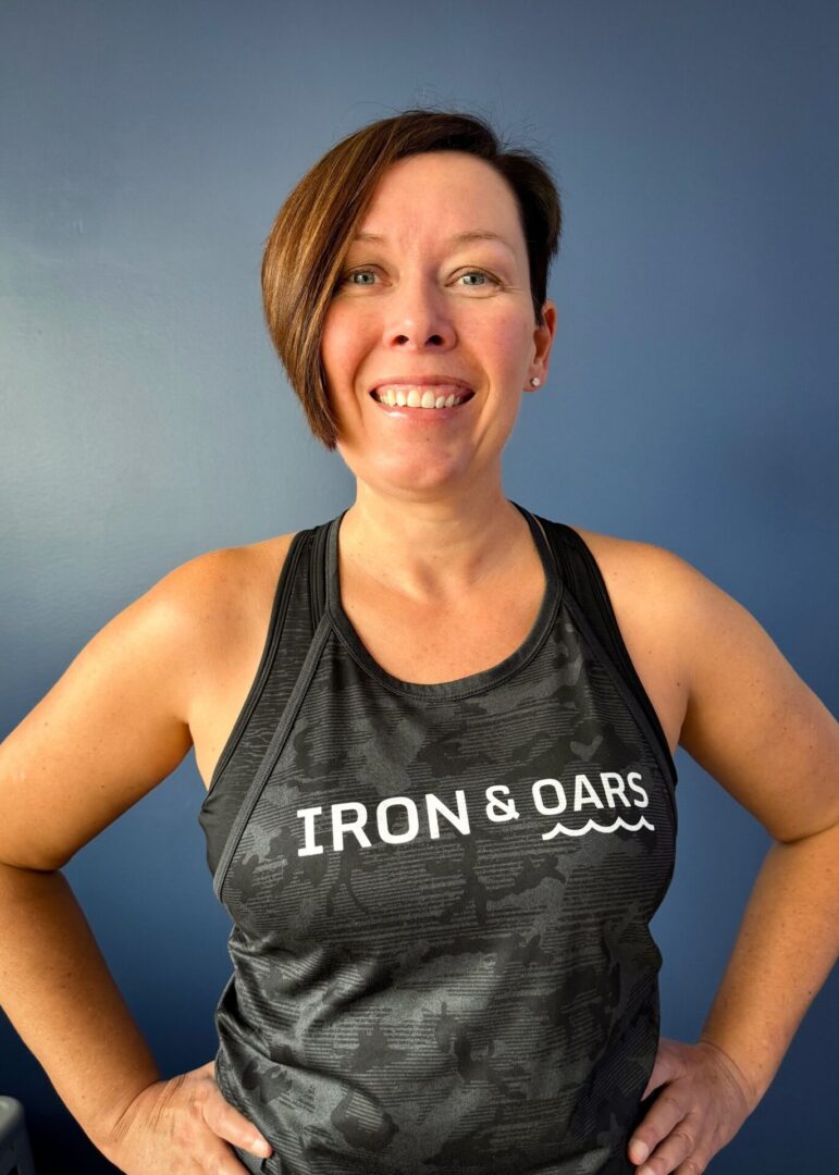 A woman wearing a black tank top with iron and oars on it.