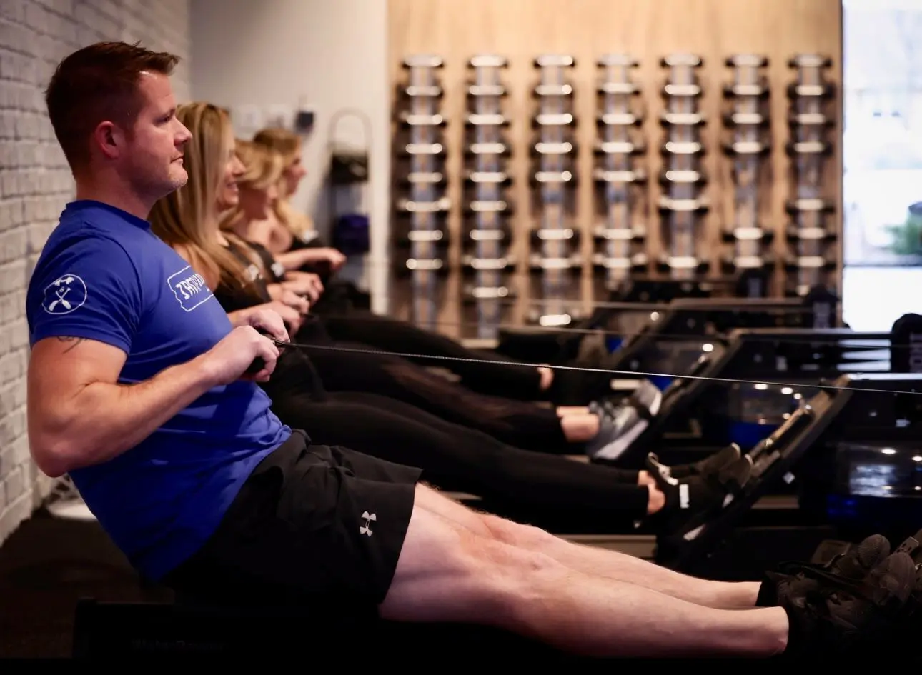 A man and woman are sitting on rowing machines.