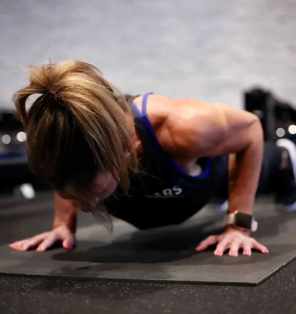 A woman is doing push ups on the floor.